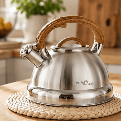 Stainless steel kettle with wooden handle on a woven mat in a kitchen setting