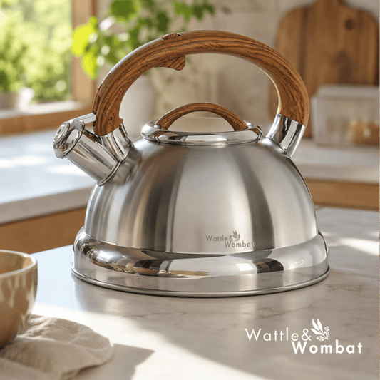 Stainless steel kettle with wooden handle on a kitchen counter, featuring the Wattle & Wombat brand.